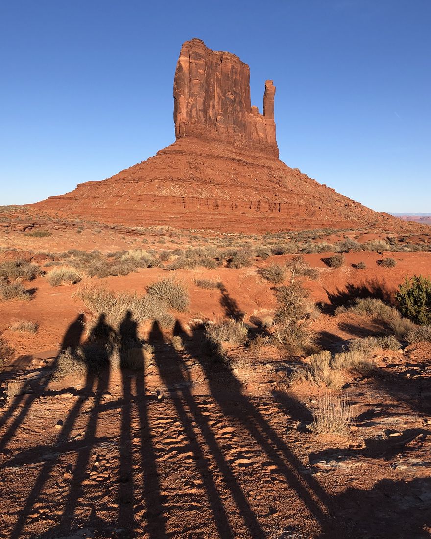 Les ombres des cinq membres de l'équipe devant une butte de Monument Valley
